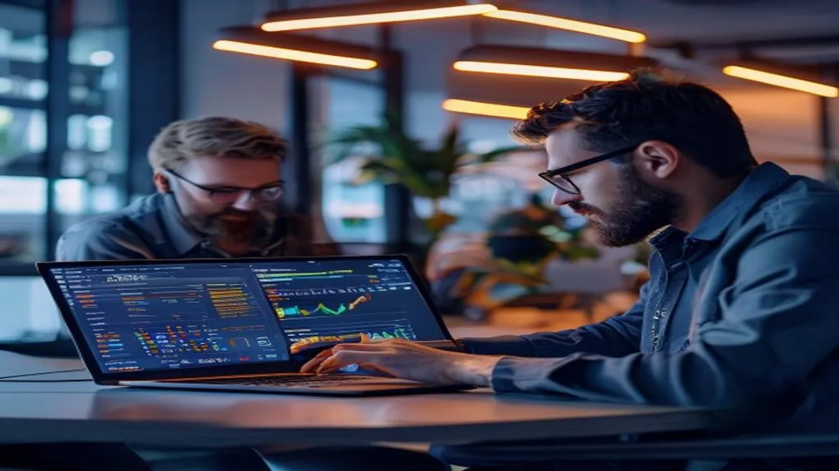 Two web developers pair-programming, pointing at performance metrics on a laptop